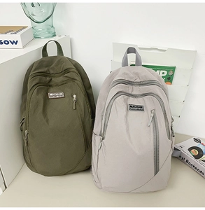 Detail view of large capacity nylon backpacks in olive green and light grey on a desk