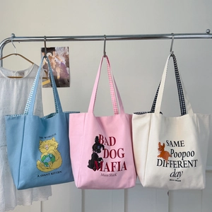 Three canvas tote bags with cat and dog prints and plaid handles hanging in a room
