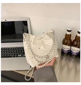 Détail du sac seau blanc crème avec chaîne perlée, pendentif étoile et matelassage