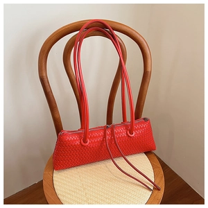 Close-up of red woven leather shoulder bag showing the fine texture and silver zipper
