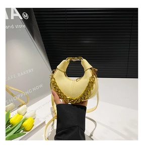 Detail of lychee textured leather and gold chain on crescent bag with a floral background