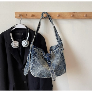 Detail of blue washed denim tote bag showing metal eyelets and adjustable strap