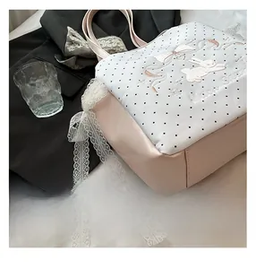 Détail du sac cabas rose à pois avec broderie de lapin et bordure en dentelle blanche