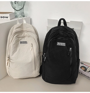 Macro detail of high-capacity nylon backpacks in beige and black with multi-pocket design