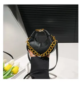 Detail of black lychee grain crescent bag with chunky gold chain and leather strap