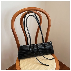 Close-up of black woven leather texture and silver zipper detail on underarm bag