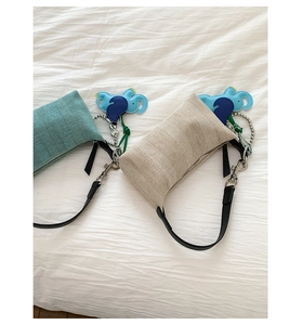 Detail view of woven texture armpit bags in cyan and off-white with elephant charms