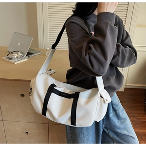 Dettaglio di una borsa a tracolla cilindrica bianca con cinghie in tessuto nero a contrasto