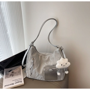 Detail of silver metallic dumpling bag featuring a soft cloud pendant in a modern setting