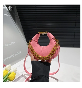 Detail of pink lychee leather crossbody bag with chunky gold chain strap and metal clasp