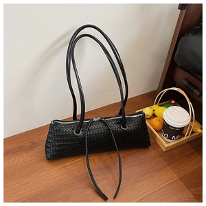 Macro view of detailed hand-woven texture and black leather straps on the shoulder bag