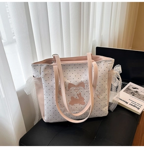 Detail der weißen Polka-Dot-Tasche mit rosa Kaninchenstickerei und Spitzenschleifen