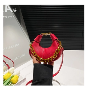 Detail of red lychee grain leather crescent bag with gold chain and thin shoulder strap