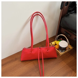 Detailed macro view of vibrant red woven leather texture on a chic baguette shoulder bag