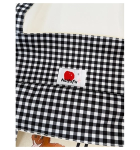 Detailed view of checkered fabric seams with a cute dog print and brand label on canvas
