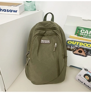Detailed close-up of an olive green nylon backpack with front pocket and logo detail