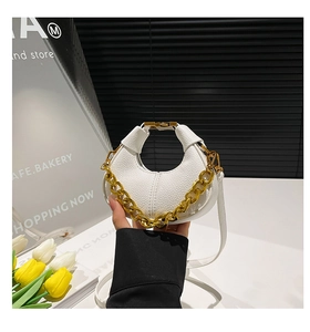 Detail of white lychee texture crescent bag with chunky gold chain handle and slim strap