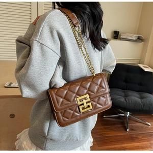 Sac à chaîne matelassé marron avec boucle dorée, porté à l'épaule pour un look élégant