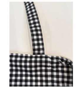 Detail of the stitching on a black and white gingham canvas tote with cream zipper