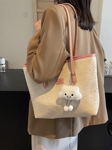 Grande borsa tote beige con motivi a rilievo e tracolle in pelle rosa indossata