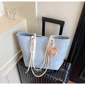 Detail of light blue faux crocodile skin tote bag with cream straps and bear charm decoration