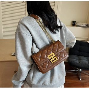 Détail de la texture en cuir matelassé marron et boucle en métal doré du sac à bandoulière