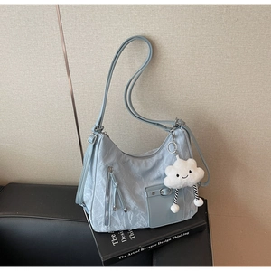 Detail of light blue hobo bag with pleated texture and white cloud plush charm