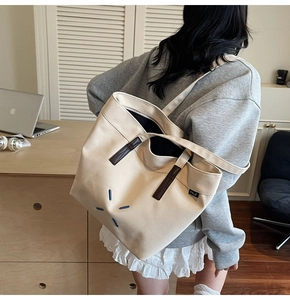 Detail view of large canvas tote bag featuring star pattern and brown leather handle