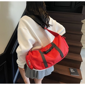 Dettaglio della borsa sportiva rossa cilindrica con ampie tracolle nere e tasche ampie