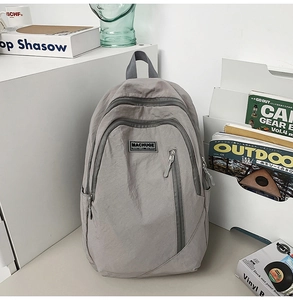 Detail view of the gray casual backpack showing durable fabric and front brand logo label