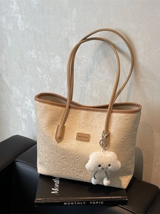 Borsa tote beige con motivi a rilievo, manici marroni e ciondolo a forma di nuvola bianca