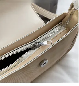 Detailansicht des glatten silbernen Reißverschlusses und der cremefarbenen Karomuster-Tasche
