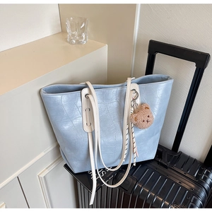 Close-up of light blue crocodile embossed tote bag with a cute brown plush bear charm