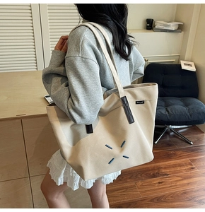 Detail of canvas tote bag with contrast handles and TCLN label on side view