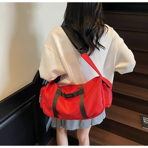 Dettaglio della borsa cilindrica in nylon rosso con tasca laterale e tracolla nera