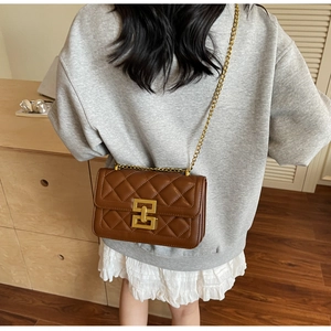 Détail d'un sac à bandoulière matelassé marron avec fermoir carré doré et bandoulière chaîne