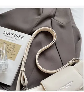 Detail der cremefarbenen Ledertasche mit MIKAXIQI-Logo und elegantem Riemen-Design