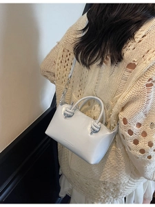 Minimalist light blue crossbody pillow bag with knot handles shown on a model