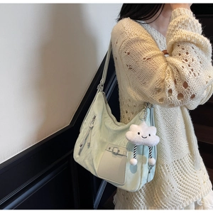 Detail of mint green shoulder bag with decorative zipper and white cloud plush charm