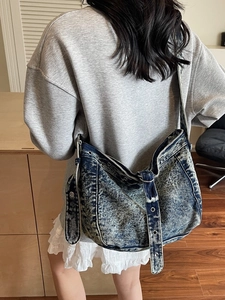 Vintage acid wash denim tote bag with oversized metal eyelets shown on female model