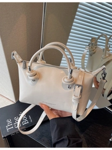 Minimalist off-white leather crossbody pillow bag with dual handles and mirror reflection