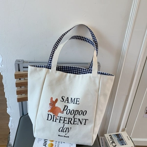Detail of canvas tote bag with orange cartoon print and stylish checkered lining
