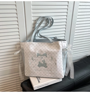 Detail der weißen Polka-Dot-Tasche mit blauer Hasenstickerei und Spitzen-Schleifen