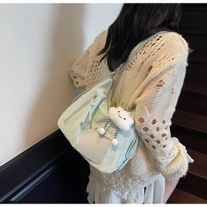 Close-up of light green nylon tote bag featuring side zipper pocket and cloud charm accessory