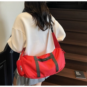 Dettaglio borsa sportiva a cilindro rossa in nylon con cinghie grigie sul retro