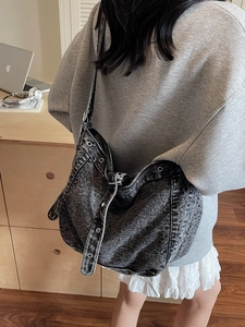 Large washed denim hobo shoulder bag with eyelet details shown on model in home setting