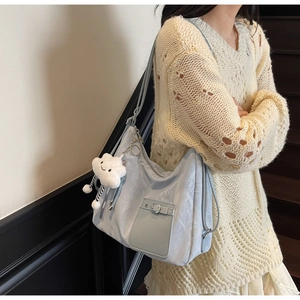 Close-up of light blue hobo bag with pleated texture and white cloud charm on strap
