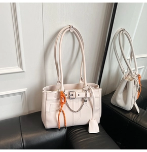 Détail du sac cabas crème avec chaîne argentée, cordon orange et étiquette en cuir