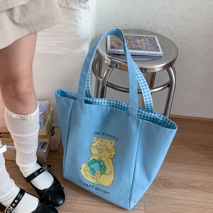 Detail of light blue canvas tote bag showing cat illustration and blue plaid lining