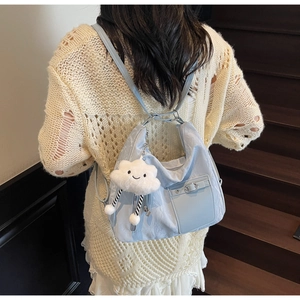 Light blue versatile backpack with cute cloud plush charm on a beige knit sweater background